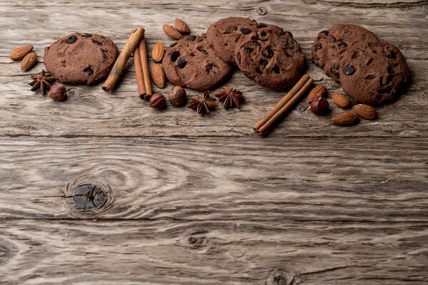 Домашнее печенье с орехами, коричными палочками и анисовыми звездами на деревянном фоне, вид сверху с копировальным местом
