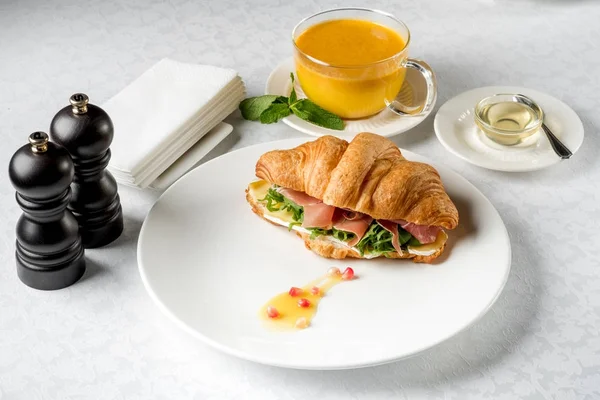Fresh croissant sandwich with tea cup