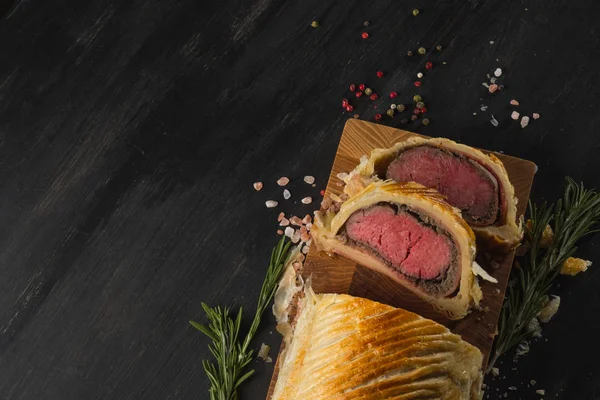 top view of sliced beef wellington on wooden board, copy space