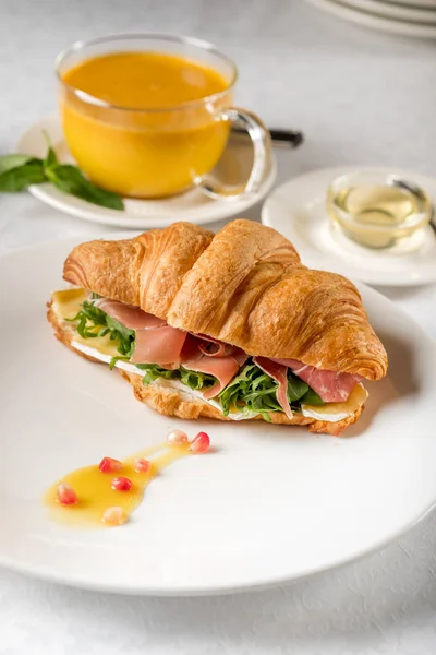 Fresh croissant sandwich with tea cup