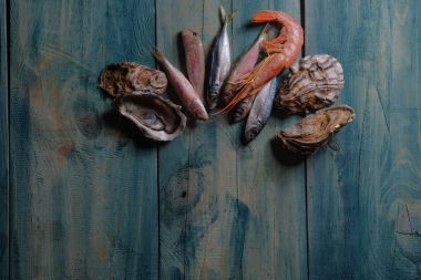 Mavi ahşap bir masa üzerinde balık ve deniz ürünleri istiridye. Yer alan metin ve menü tasarımı için. Yatay görünüm