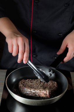 Erkek el siyah metal kızartma tavası içinde baharatlar ile et pişirme Close-Up