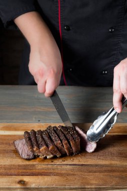 Erkek el ahşap tahta masa arka plan üzerinde ızgara et kesim Close-Up  