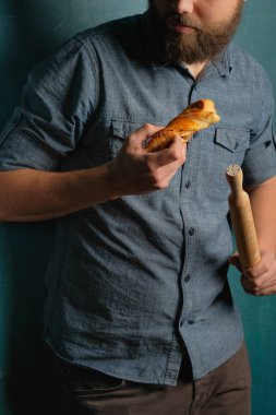 Sakallı adam ev yapımı kek ve oklava eller üzerinde mavi arka plan ayakta tutan 