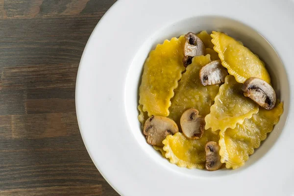 Pasta ravioli with mushrooms in dark light background. Homemade traditional Italian food photo.