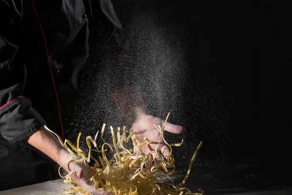 シェフのパスタ スパゲッティ パウダリング暗い黒い背景に小麦粉料理の手 — ストック写真