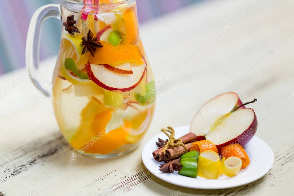 close-up of homemade healthy tea with apple, anise, lemon and cinnamon sticks in glass tea pot on table