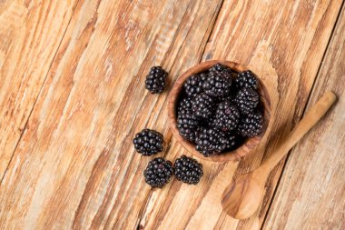 böğürtlen masada kaşıkla ahşap kase, kopya alanı ile üst görünüm