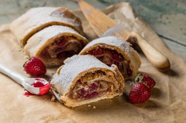Strudel pasta ile taze çilek, fındık ve pudra şekeri mavi bir vintage ahşap arka plan üzerinde