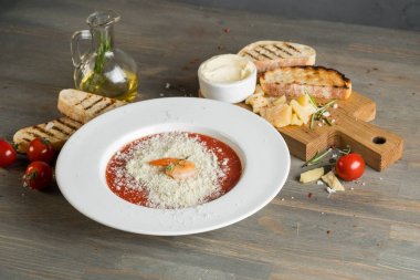 Domates çorbası kruton ekmek ve karides ahşap gri mutfak masasında