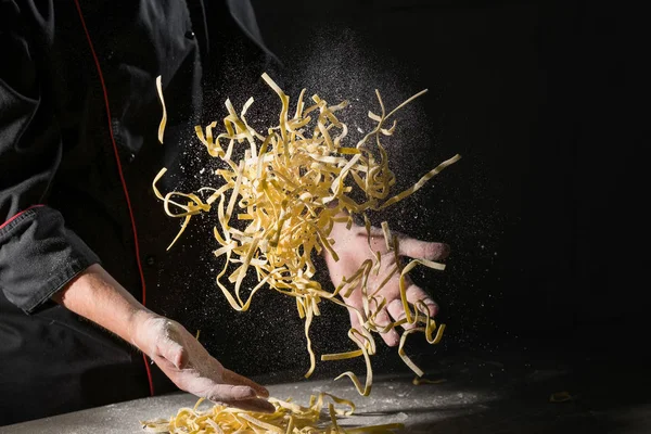 シェフのパスタ スパゲッティ パウダリング暗い黒い背景に小麦粉料理の手 — ストック写真
