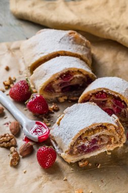 Strudel pasta ile taze çilek, fındık ve pudra şekeri mavi bir vintage ahşap arka plan üzerinde