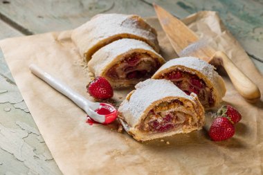 Strudel pasta ile taze çilek, fındık ve pudra şekeri mavi bir vintage ahşap arka plan üzerinde
