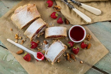 Strudel rustik tarzı mutfağı tablo arka plan üzerinde çilek ile yemek. Yukarıdan düz görünüm, top