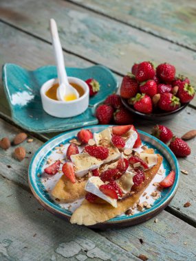 İki tost veya çilek, fındık ve peynir ile bruschetta camembert mavi ahşap rustik arka plan üzerinde. Üst yan görünüm, seçici odak
