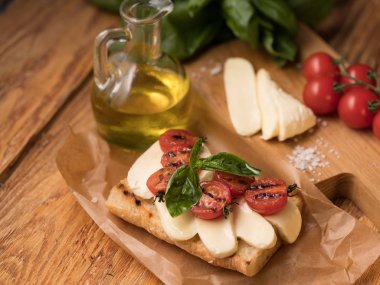mozzarella peyniri ve zeytinyağı tablo ile parşömen kağıt üzerine domates ile lezzetli sandviç Close-Up