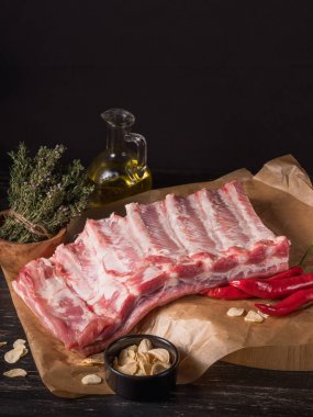 Kuru otlar ve zeytinyağı Parşömen kağıdı arka plan üzerinde Cam Kavanoz ile çiğ dana kaburga Close-Up