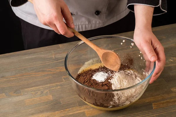 Cooking chocolate dessert with ingredients by cook hands on wooden table background.