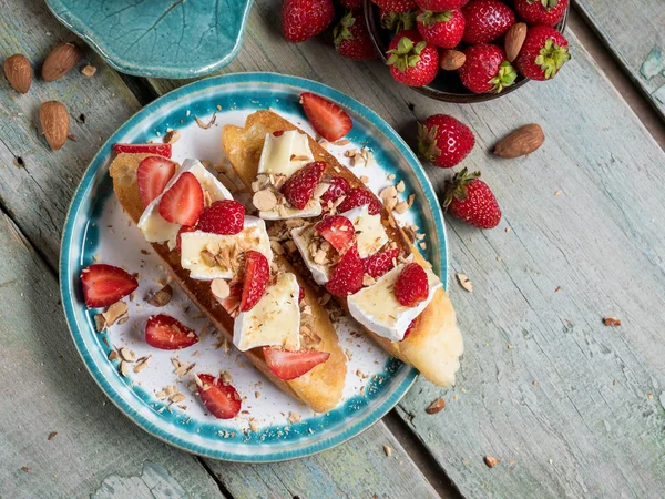 Bruschetta ile çilek, fındık yemek ve mavi ahşap rustik özgeçmişlerine camembert peyniri. Üstten Görünüm, düz yatıyordu, yukarıdan