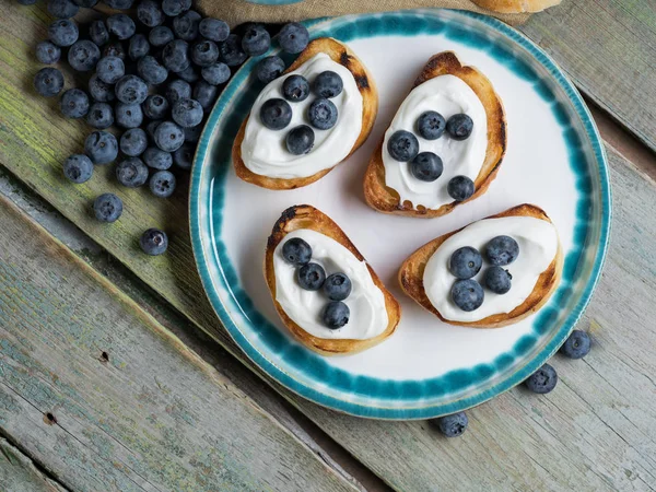 Sweet berry crostini sandwiches with ricotta and blueberries on the whole grain bread bruschetta. Rustic food recipe