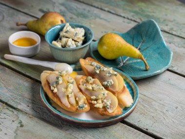 baget yumuşak dor mavi peynir, armut ve ahşap masa üzerinde tabakta bal ile yakın çekim