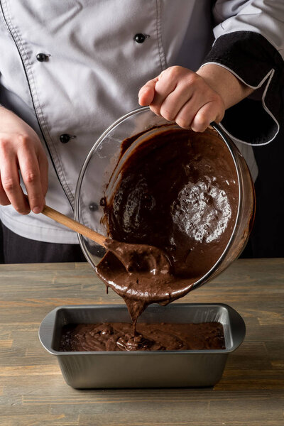 Cooking chocolate dessert by cook hands on wooden table background.