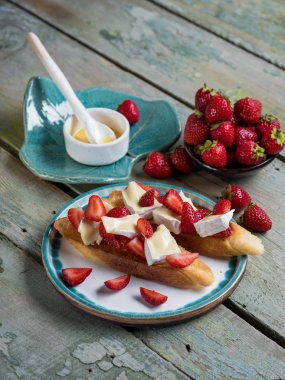 Sandviç çilek, peynir, camembert, brie, fındık ve bal ile bütün ekmek bruschetta ahşap mavi ışık arka plan üzerinde tahıl