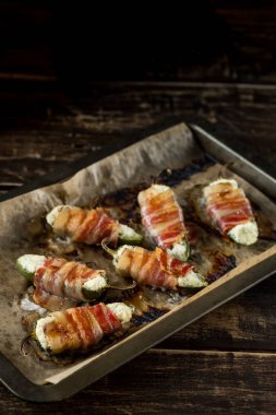 Sıcak baharatlı biber - peynir ve domuz pastırması ile doldurulmuş ve pişmiş jalapeno. Ahşap arka plan üzerinde yemek tarifi. Kopya alanı