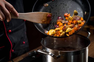 erkek Şef elleri kızarmış sebze içine koyarak pan, yakın çekim