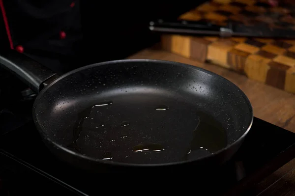 Hot frying pan with oil prepared for cooking in kitchen
