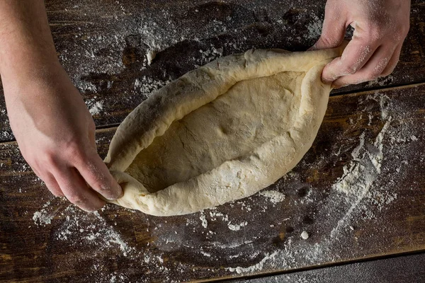小麦粉の粉で木製テーブルの上生生地でピザ フォームを作るシェフの手のクローズ アップ — ストック写真