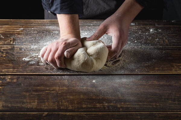 chefhands preparing tough over wooden background, top view
