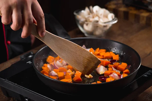 male chef hand frying vegetables in pan, close up