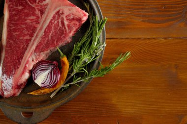 yakın çiğ et soğan, biber ve biberiye ahşap masa üzerinde metal plaka üzerinde çekim
