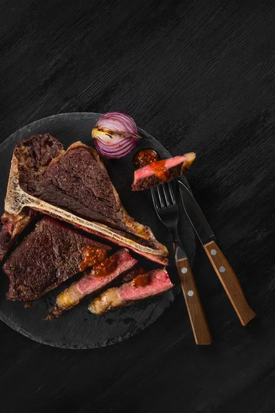 黒い板の背景にスパイスと肉のグリル — ストック写真