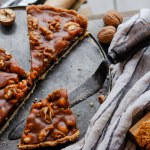 Close-up of homemade sweet chocolate pie with walnuts near grey scarf and knife