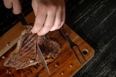 Elinde bıçakla ve baharat ahşap tahta arka plan ile ızgara et oyma erkek eller 