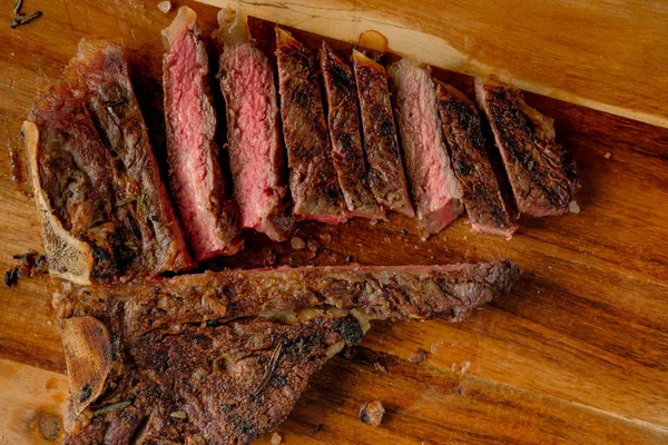 carving grilled meat with spices on wooden board background