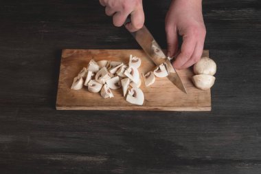 bıçak ve kesme mantar ahşap tahta arka plan üzerinde holding erkek Şef eller Close-Up