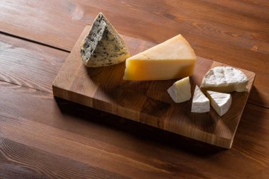 lezzetli peynir Parmesan, Camembert ve mavi peynir tablo arka plan üzerinde ahşap kesme tahtası üzerinde kümesi Close-Up