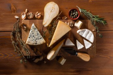 lezzetli peynir Parmesan, Camembert ve mavi peynir ile fındık, baharatlar ve ahşap kesme tahtası tablo arka plan üzerinde bıçak kümesi Close-Up