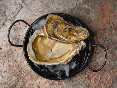 buz üzerinde taş zemin üzerine siyah metal kase taze lezzetli açık istiridye Close-Up