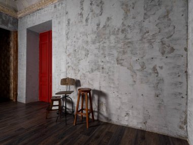 vintage wooden chairs in room with grey concrete wall and red door clipart