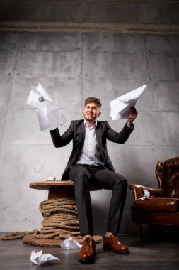 Tahta masada oturan ve kağıtları çöpe kızgın genç işadamı