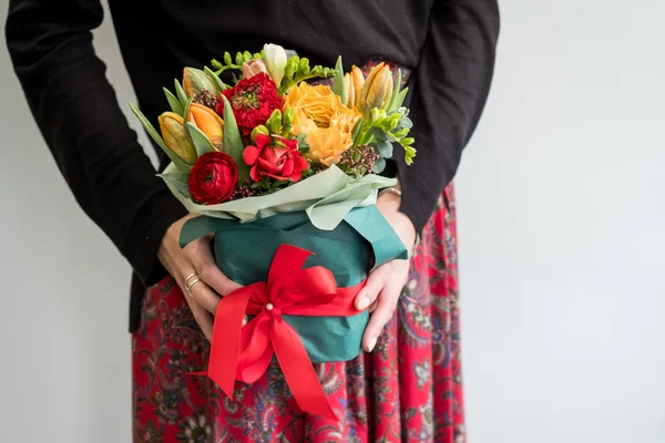 赤とオレンジの花のスタイリッシュな花束を持って女性の花屋 — ストック写真
