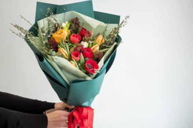 Şık buket kırmızı ve turuncu çiçek tutan kadın çiçekçi