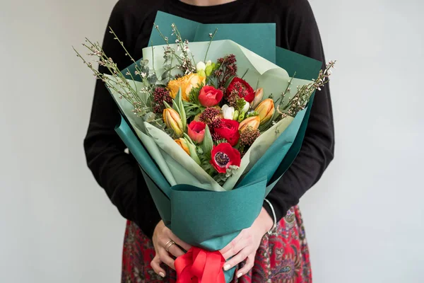 Female florist holding stylish bouquet of red flowers