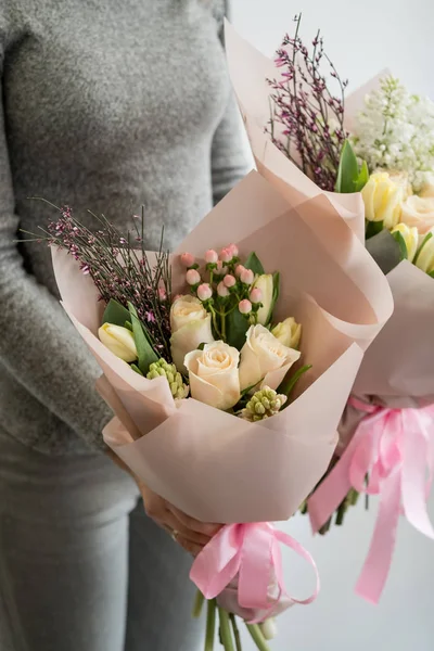 Woman holding two stylish bouquets of tender flowers