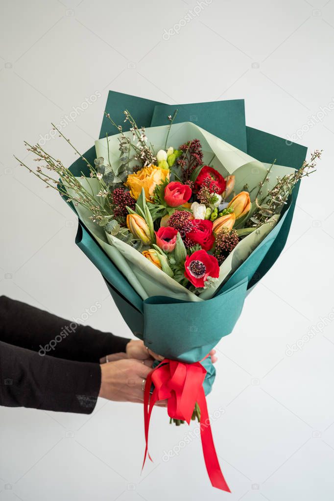 Female florist holding stylish bouquet of red and orange flowers