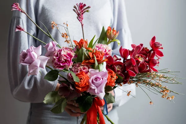 灰色の背景に美しい春の花のブーケを持って女性のファッションの写真 — ストック写真